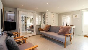 A modern living room with a grey sofa, wooden coffee table, and a flat-screen TV. - Mariners Cottage (Aldeburgh)