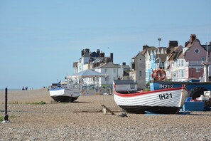 A beach with several boats moored on the pebbled shore, a lifebuoy, and a building with a sign reading "South Coast".