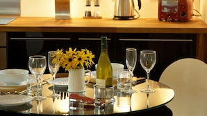 Una mesa de comedor dispuesta con copas de vino, una botella y un jarrón con flores amarillas.