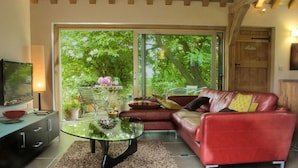 Una sala de estar con un sofá de cuero rojo, una mesa de centro de vidrio y un televisor sobre un mueble.