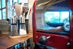 Una cafetera con exterior rojo y puerta de cristal, sobre una encimera de madera.