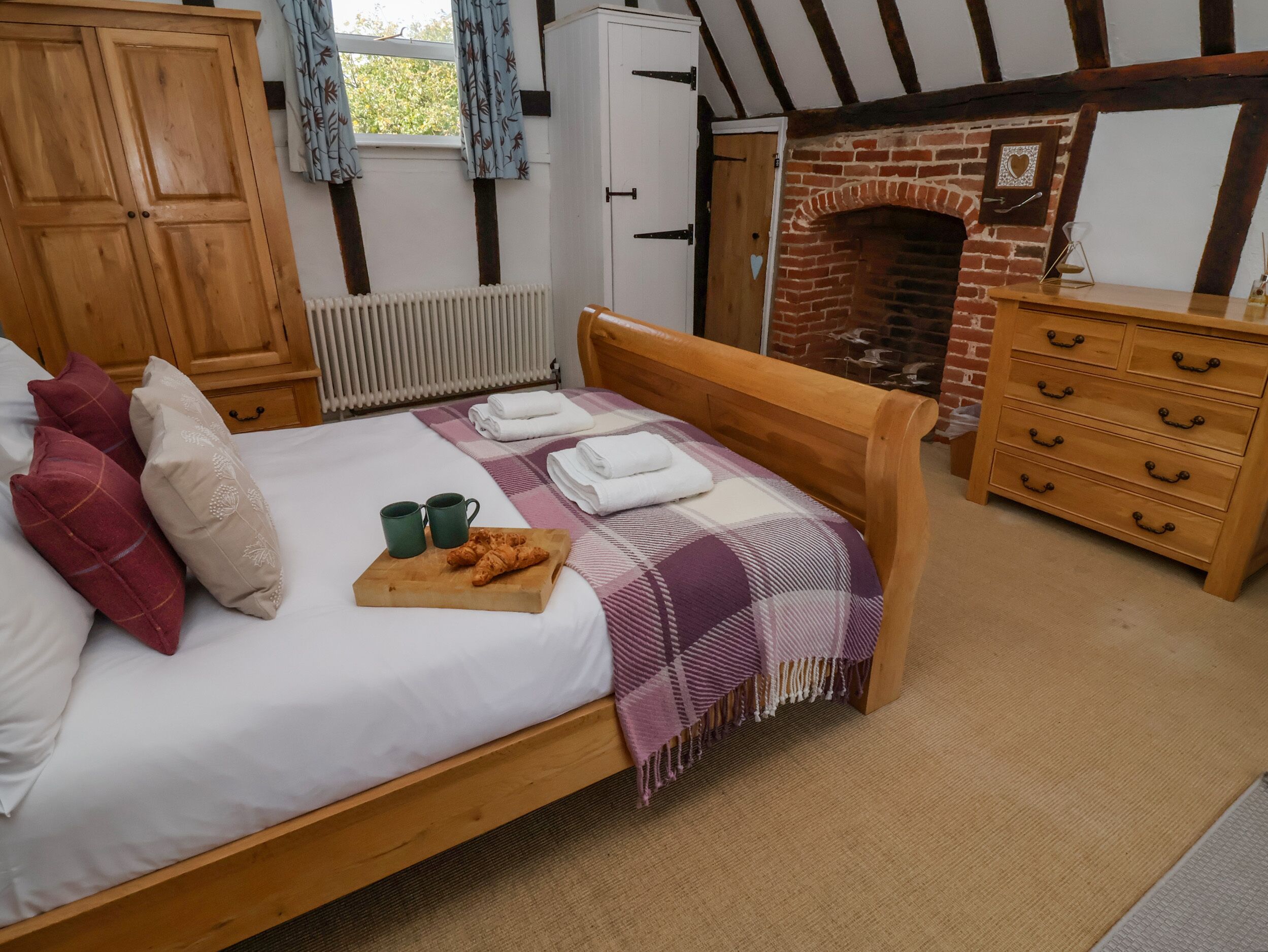Quarto com cama de madeira, lareira, guarda-roupa e radiador.