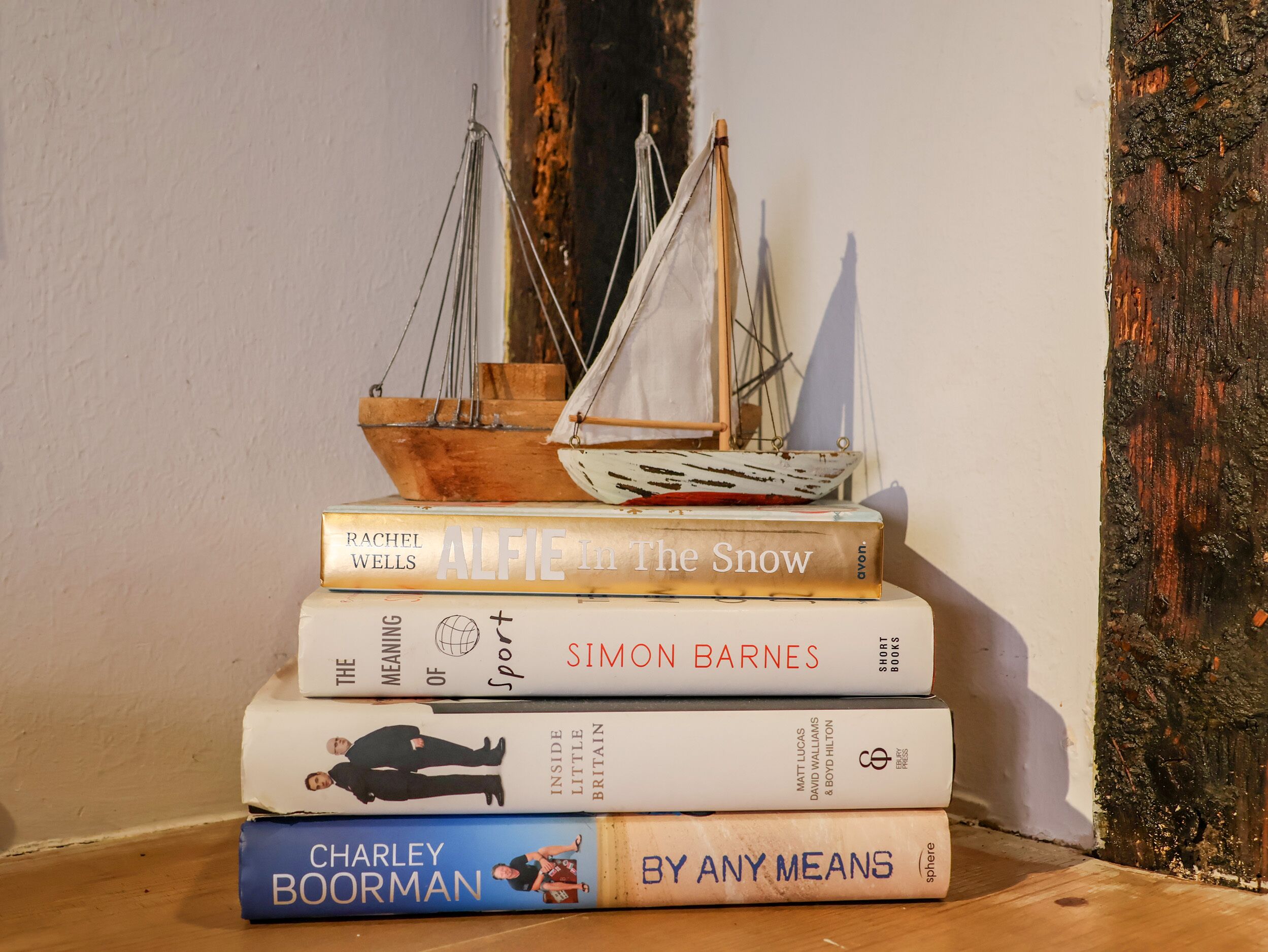 A stack of books with a small model sailboat on top.