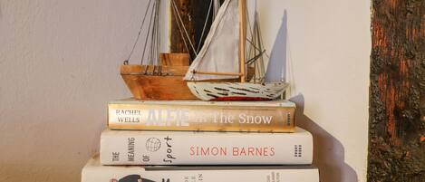A stack of books with a small model sailboat on top.