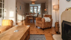 A cozy living room with a fireplace, wooden furniture, and a dining area with chairs and a table.