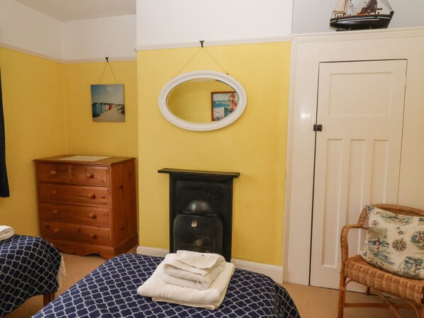 A room with two beds, a dresser, a fireplace, a mirror, and a door.