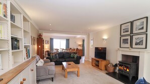 A living room with a sofa, a coffee table, a fireplace, a television, and a bookshelf. - Seadrift (Saxmundham)