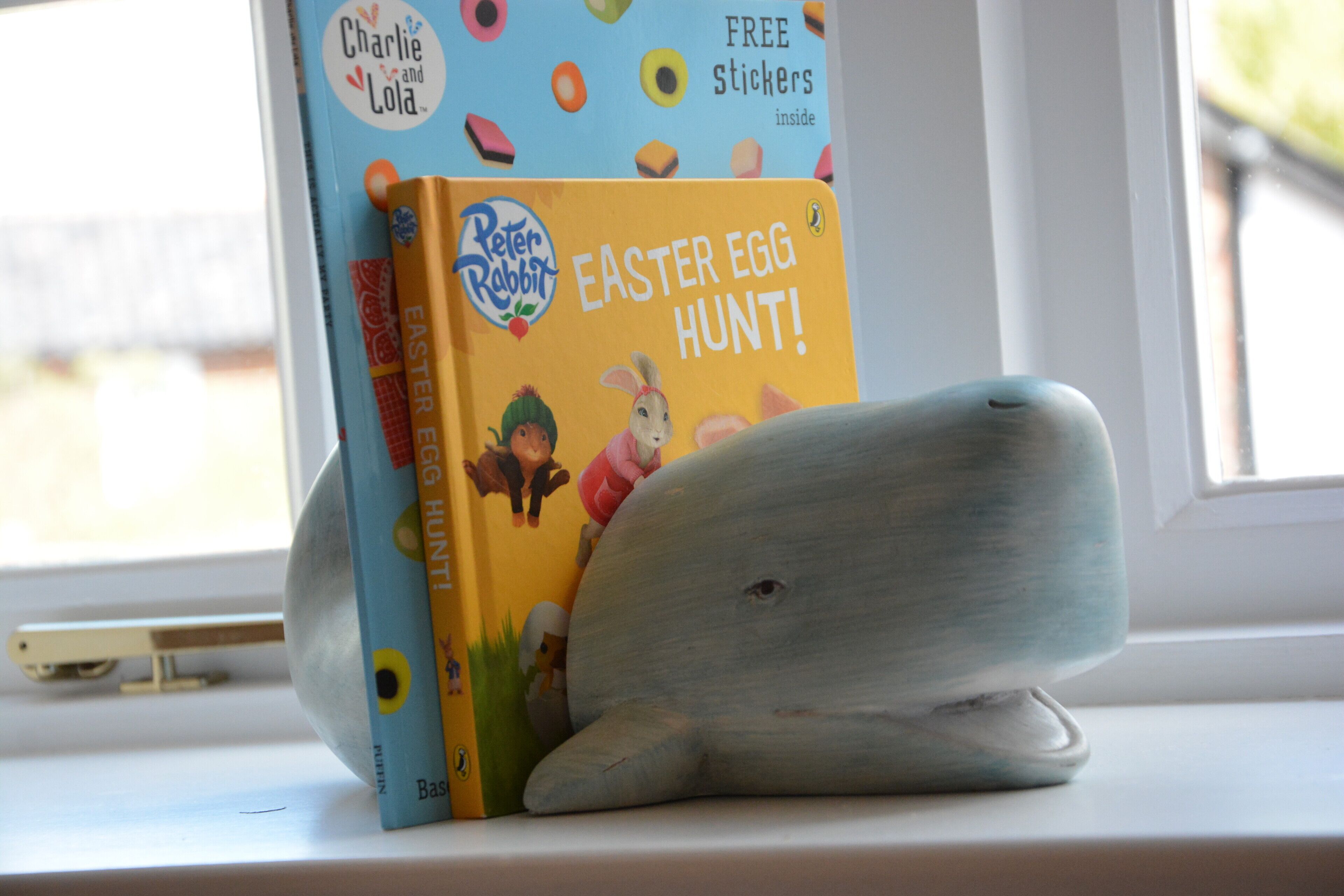 A book titled 'Easter Egg Hunt!' by Peter Rabbit on a windowsill.