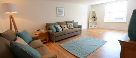 A spacious living room with a large sofa, a coffee table, and a floor lamp.