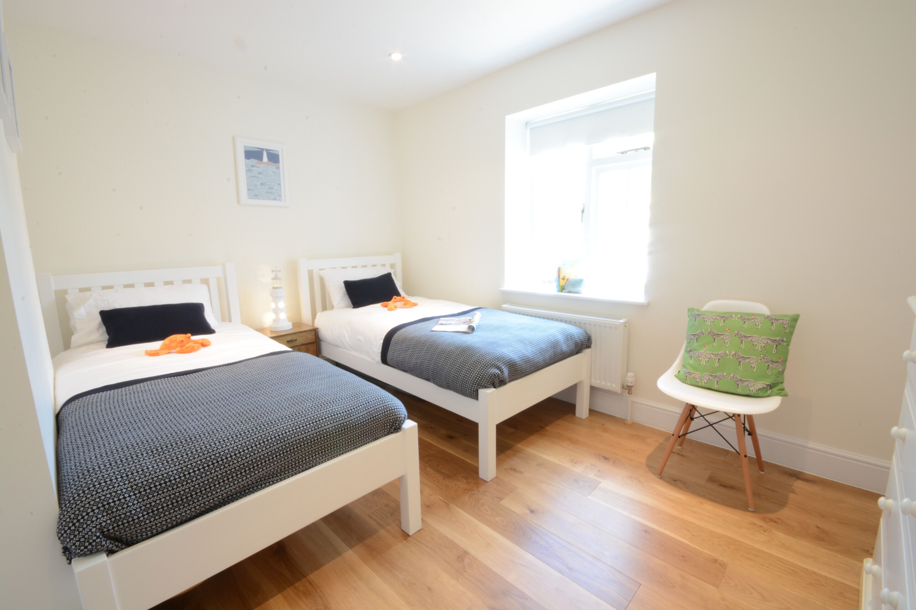 A bedroom with two single beds, a window, and a chair.