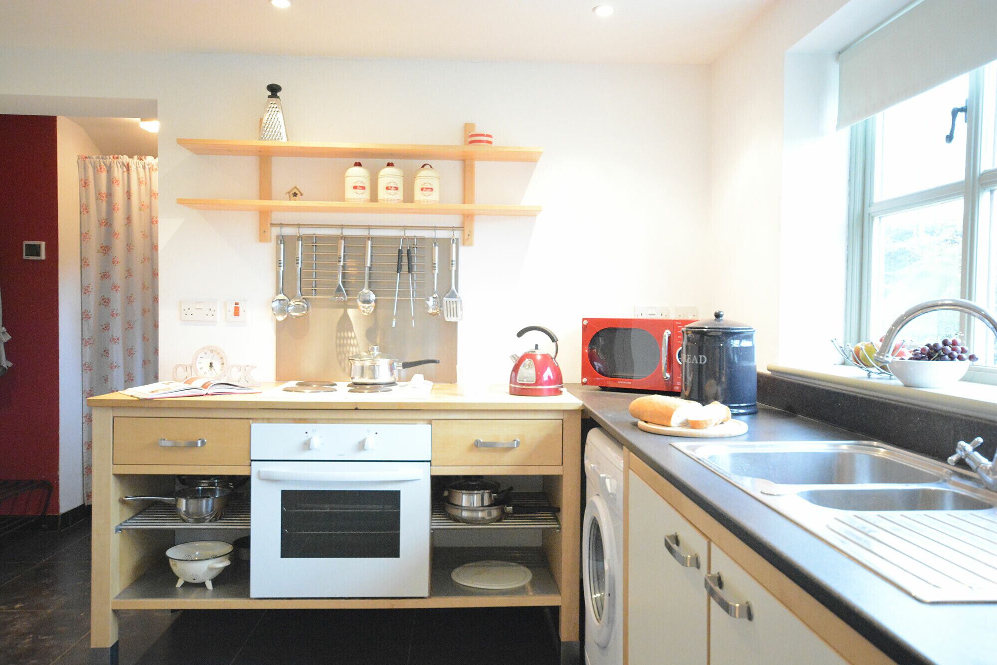 A compact kitchen with a stove, oven, microwave, and a sink.