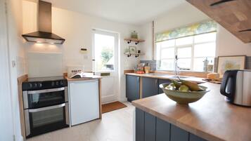 A modern kitchen with a built-in oven, a coffee maker, and a bowl of fruit on the counter.