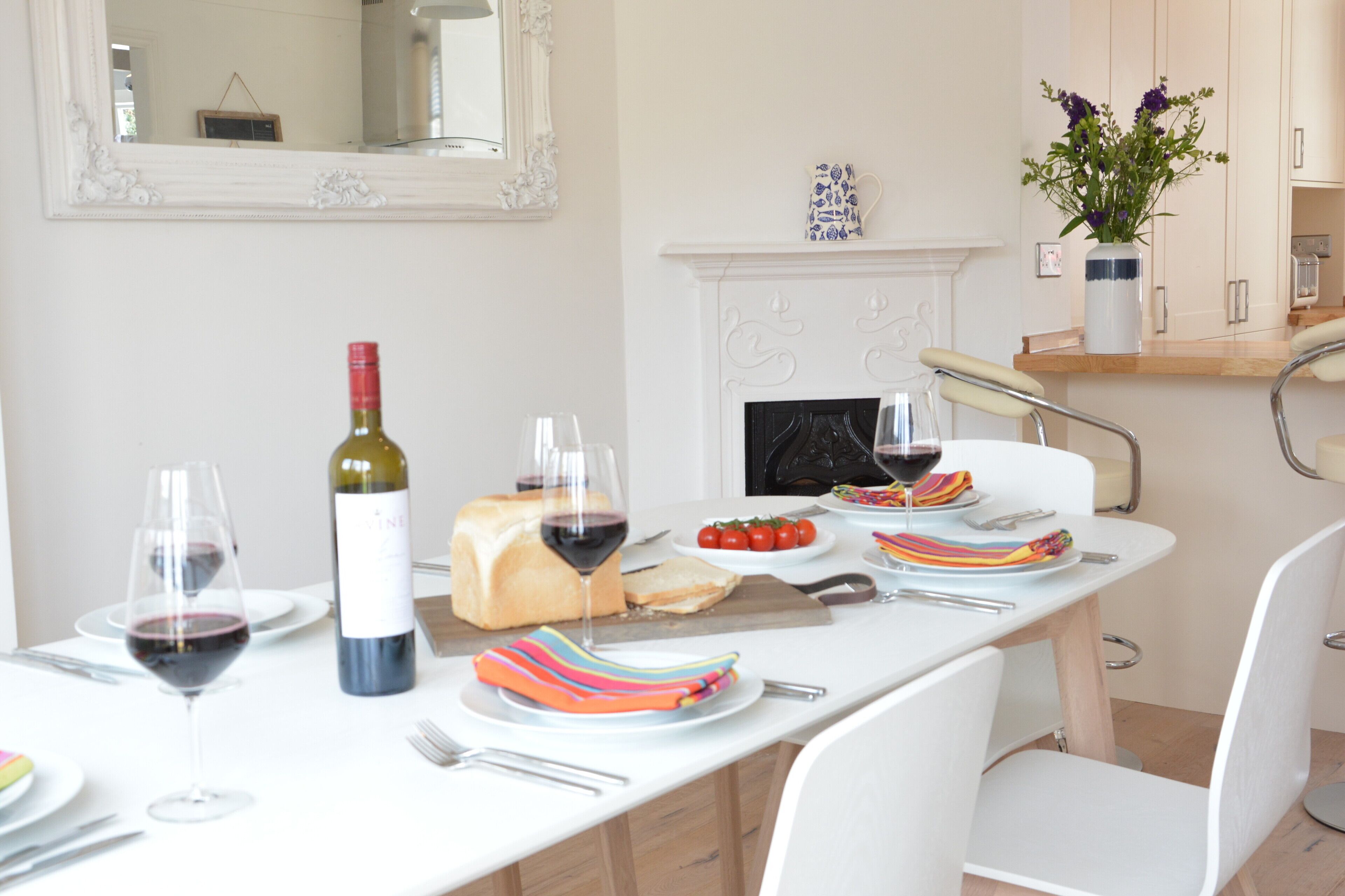 A dining table set with plates, glasses, and a bottle of wine.