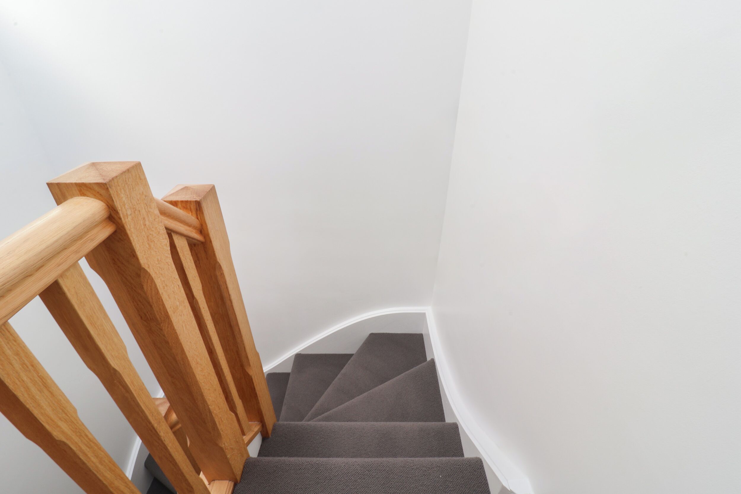 A wooden staircase with a handrail and carpeted steps.