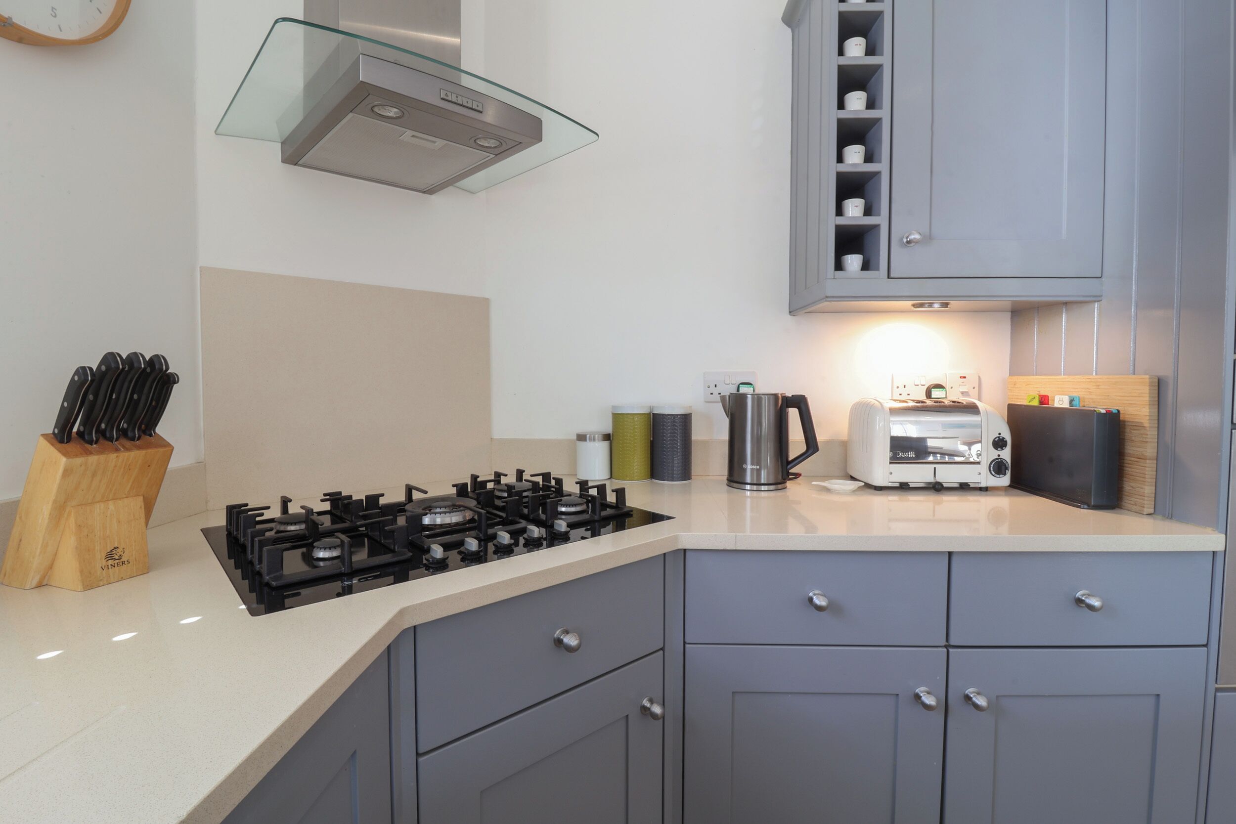 Una cocina moderna con gabinetes grises, estufa a gas, tostadora y cafetera.