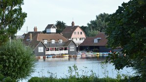 Un bâtiment situé au bord de la rivière, devant lequel sont amarrés plusieurs bateaux.
