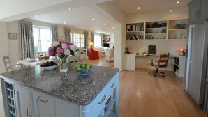 Une cuisine spacieuse dotée de plans de travail en granit, un coin repas avec une table pour deux personnes et un salon confortable avec une cheminée.