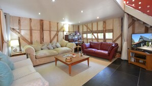 A cozy living room with a sofa, a red leather couch, and a wooden coffee table.