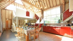 A spacious dining area with a herringbone floor pattern, wooden chairs, and a table set for a meal.