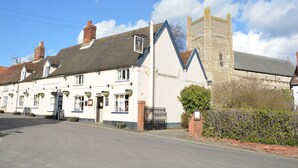Un’antica locanda con una torre in pietra, una facciata bianca e un cartello che recita 'The Kings Head Inn'.