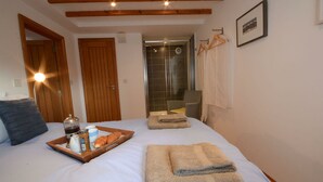 Camera d'albergo con un letto, una testiera in legno, zona doccia e portasci.