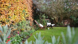 Un giardino con prato, una sedia di legno e un'altalena.