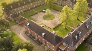 Un grand bâtiment rectangulaire doté de nombreuses fenêtres et d’une cour intérieure.