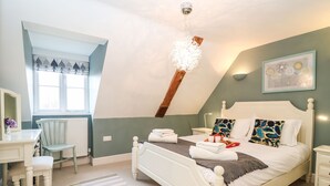 Une chambre à coucher avec un lit, une table de chevet, une chaise et une fenêtre avec des rideaux.