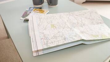 A map spread on a table with two mugs and a book.