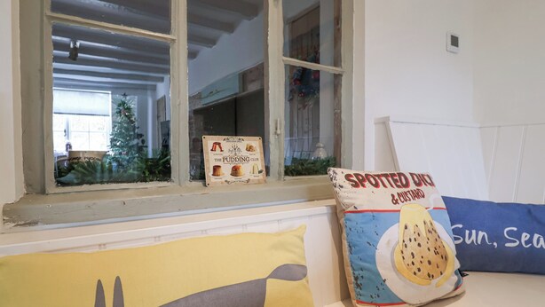 A window with a view of a Christmas tree and a sign for 'The Pudding Club'.