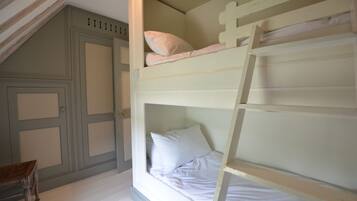Una cama litera con una escalera, una silla de madera y una puerta con paneles.