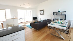 A modern living room with a sofa, dining table set for four, and a television. - Seal Cove (Reydon)