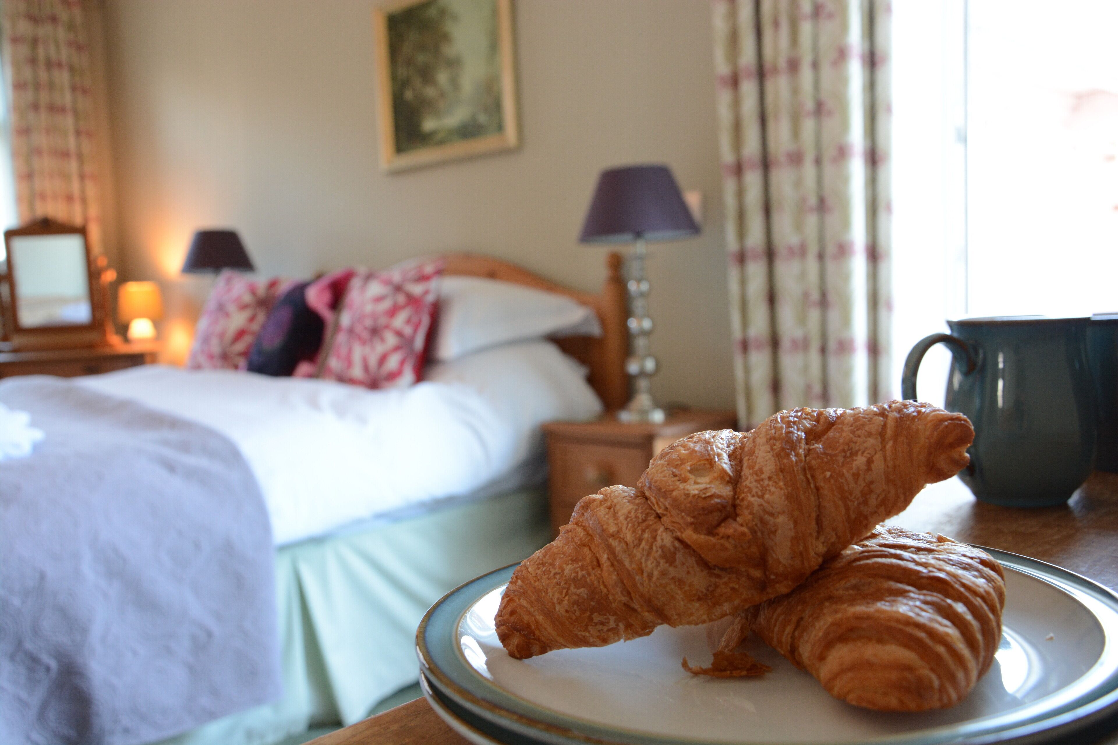 A bed with a floral bedspread, a bedside lamp, and a framed picture on the wall.