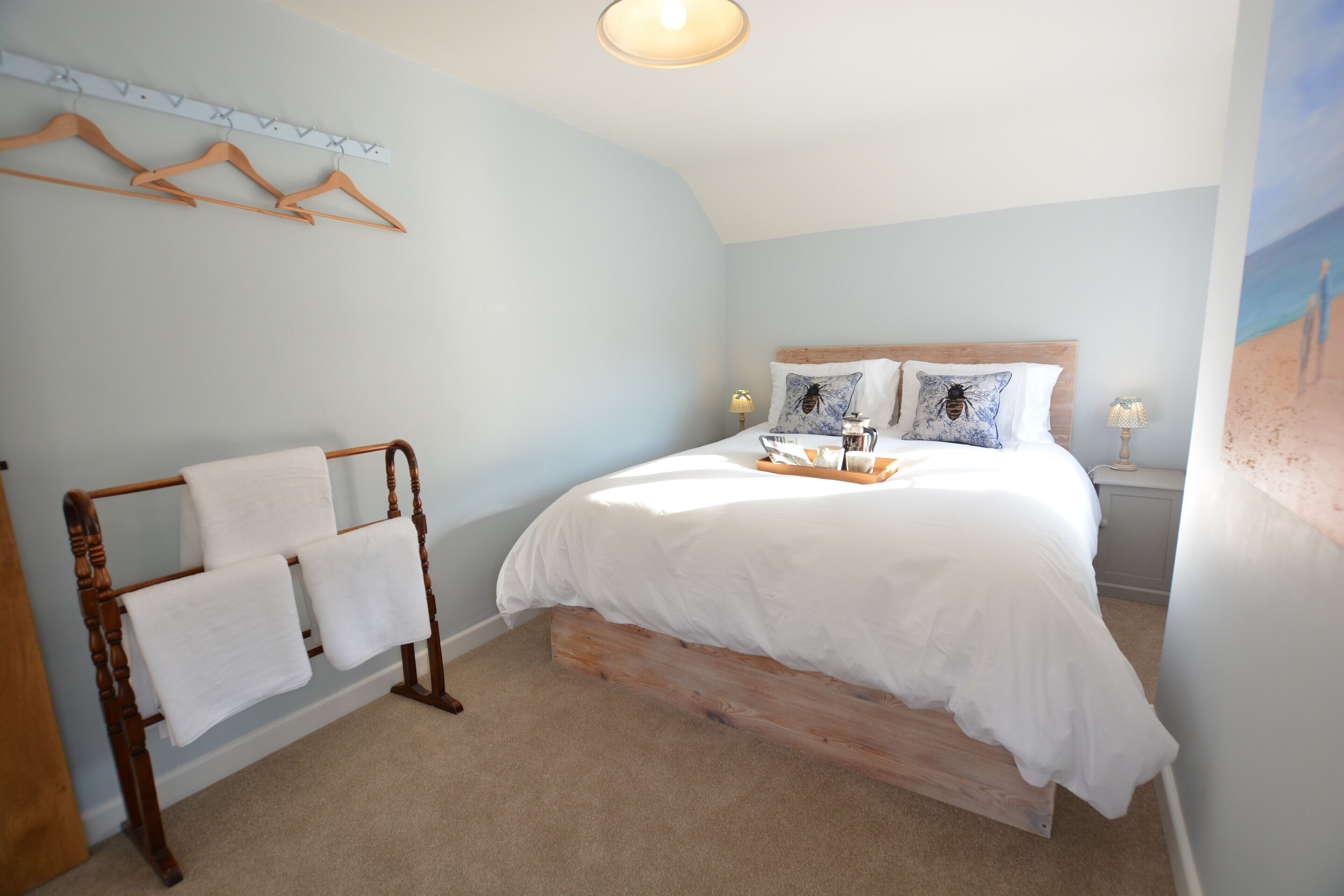 A bedroom with a wooden bed, a towel rack, and a wall-mounted light fixture.