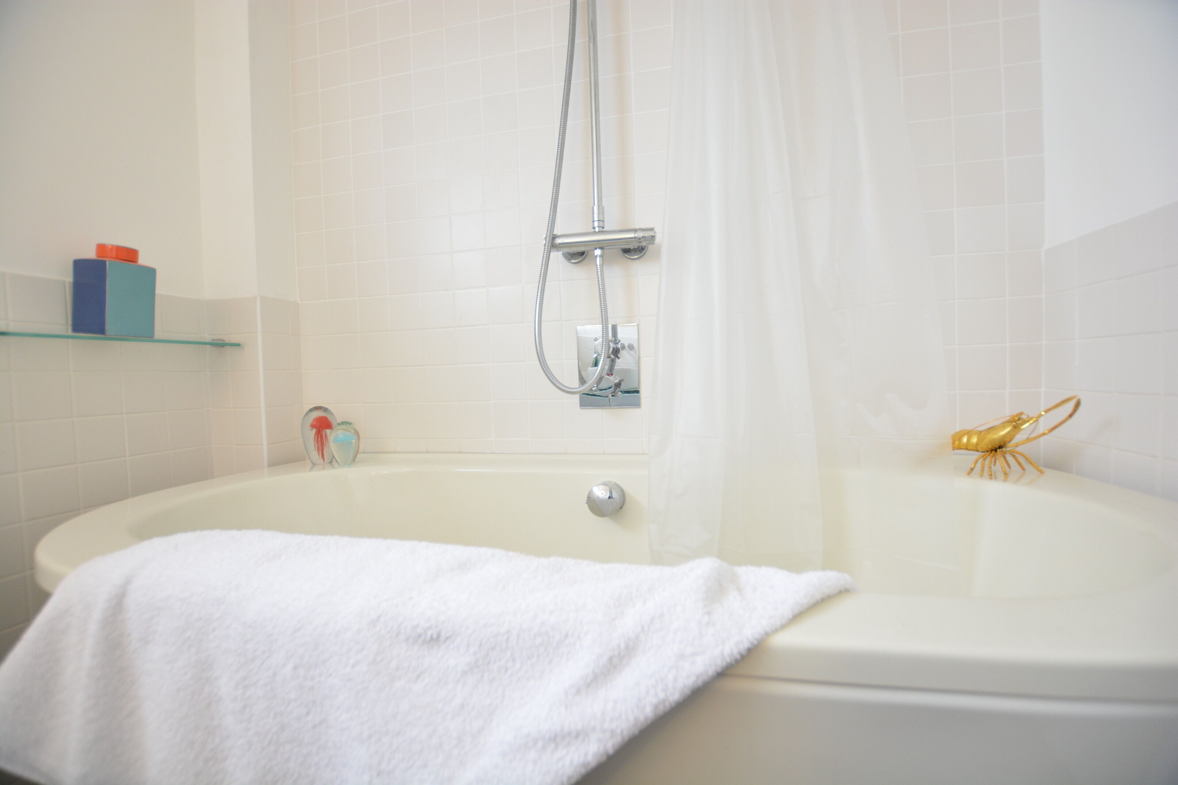 Een badkamer met een bad, een douchekop en een handdoek op de rand.