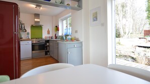 A modern kitchen with a dishwasher, oven, and a window overlooking a garden.
