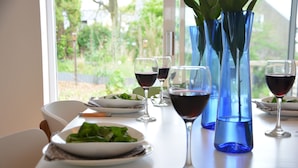 A dining table set with plates of food, wine glasses, and blue vases.