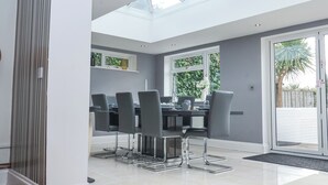 A modern dining area with a glass ceiling, grey walls, and a view of greenery outside. - Little Wissett, Aldeburgh (Aldeburgh)