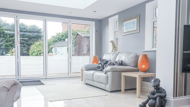 A modern living room with a grey sofa, a small wooden table, and a statue. - Little Wissett, Aldeburgh (Aldeburgh)