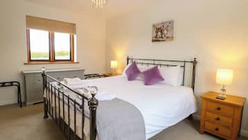 A bedroom with a bed, bedside tables, a window, and a chandelier.