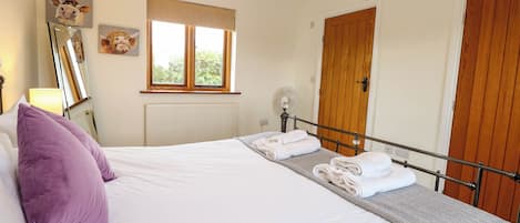 A bedroom with a bed, a window, a wooden door, and a radiator.
