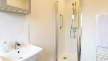 Un bagno con doccia vetro, lavabo bianco e portasciugamani.