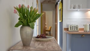 A kitchen with a wooden countertop, a vase with flowers, and a plate of grapes. - Red Poll Barn (Halesworth)