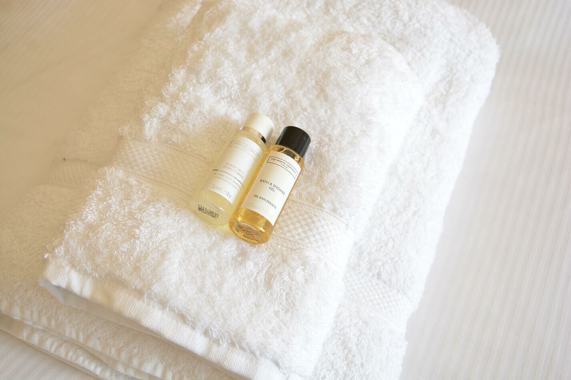 Deux bouteilles de gel pour le bain et la douche, posées sur une serviette blanche.