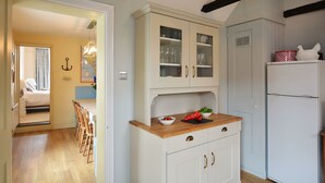 A kitchen with white cabinets, a wooden countertop, and a white refrigerator. - Walton House, Southwold (Reydon)