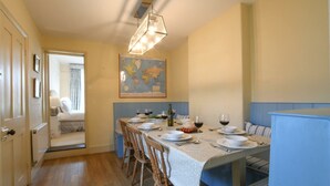A dining area with a long table set for six, a map on the wall, and a view into a bedroom. - Walton House, Southwold (Reydon)