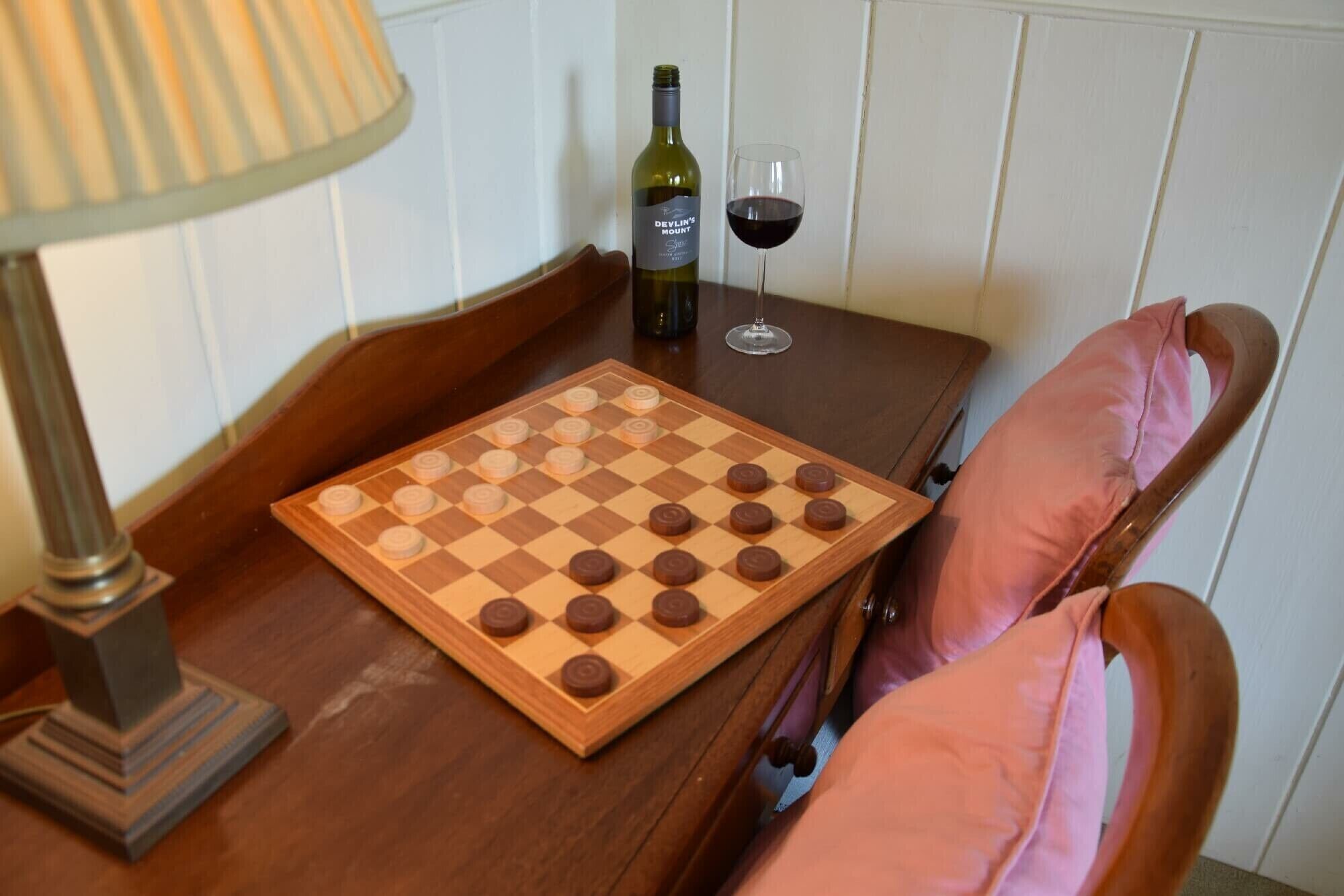 Un juego de mesa de madera sobre una mesa, una botella de vino y una copa de vino tinto.