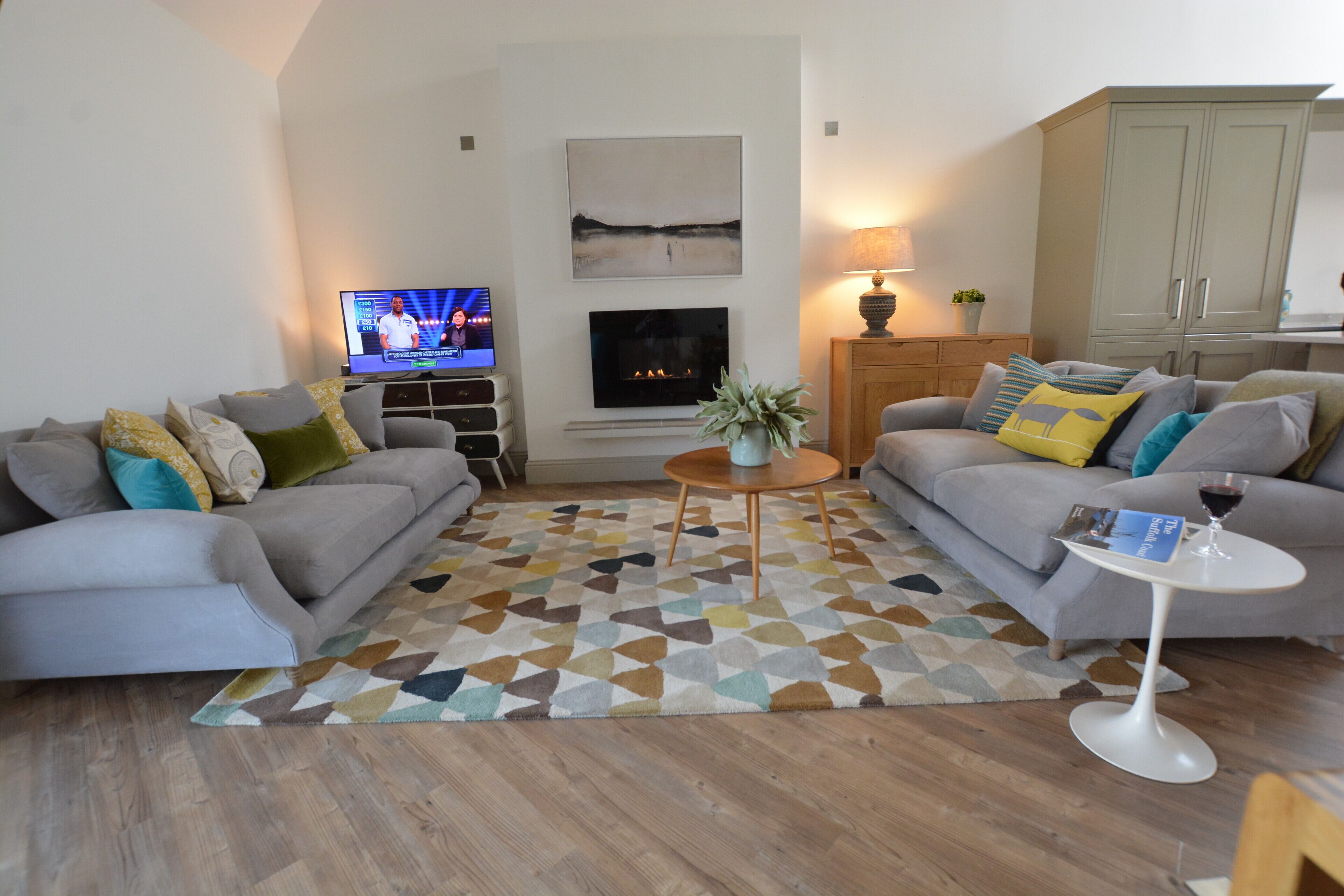 A living room with two sofas, a coffee table, a fireplace, and a television.