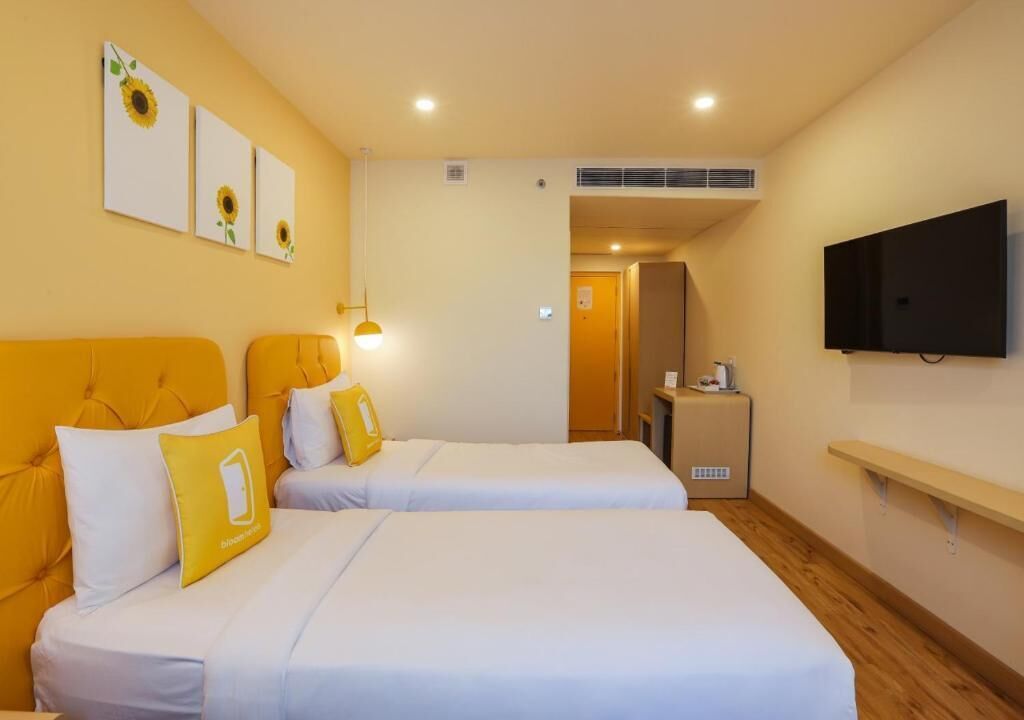 A hotel room with two beds, a TV, and artwork on the wall.