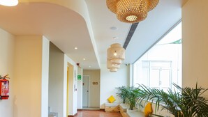Un hall d’entrée spacieux doté d’un plancher en bois, un espace d’accueil avec un banc, des plantes en pot et une grande fenêtre laissant entrer la lumière naturelle.